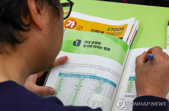  강남 한 학원의  '의약학 정시지형 설명회'에서 학부모가 책자에 적힌 의대증원 관련 내용을 읽고 있다.@사진 연합뉴스